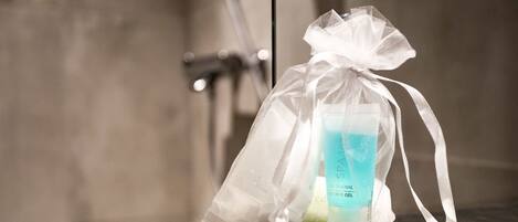 A transparent gift bag with a ribbon, containing a bottle of SPA shower gel, placed on a dark surface.