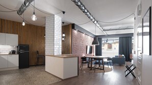 Una cocina moderna con una isla central, un comedor con mesa redonda y una sala de estar con sofá y vista a la ciudad.
