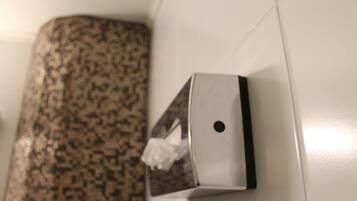 Dispensador de pañuelos adherido a una pared con un rebozo de azulejos estampados.