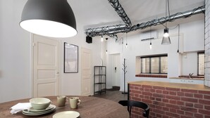 Una cocina moderna con una mesa de madera dispuesta para comer, una pared de ladrillo decorativa e iluminación colgante.