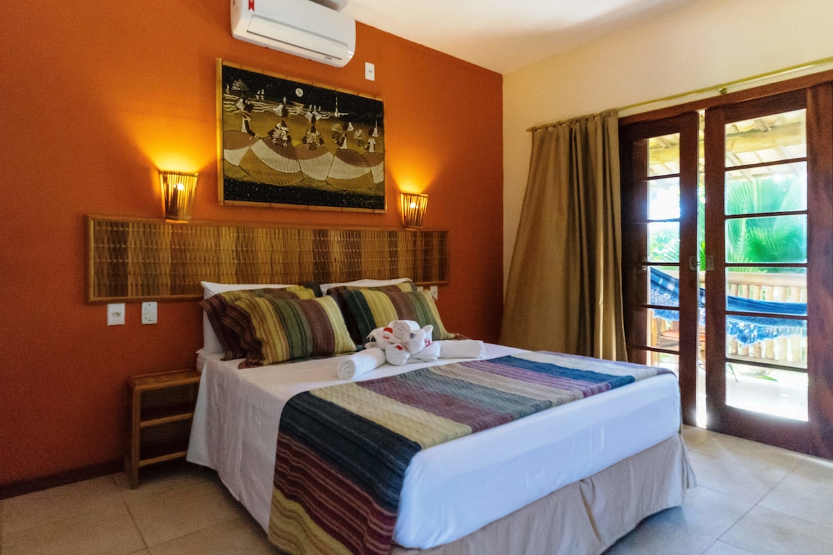 Une chambre d’hôtel avec un lit, un tableau au mur et une vue sur l’extérieur par une porte.