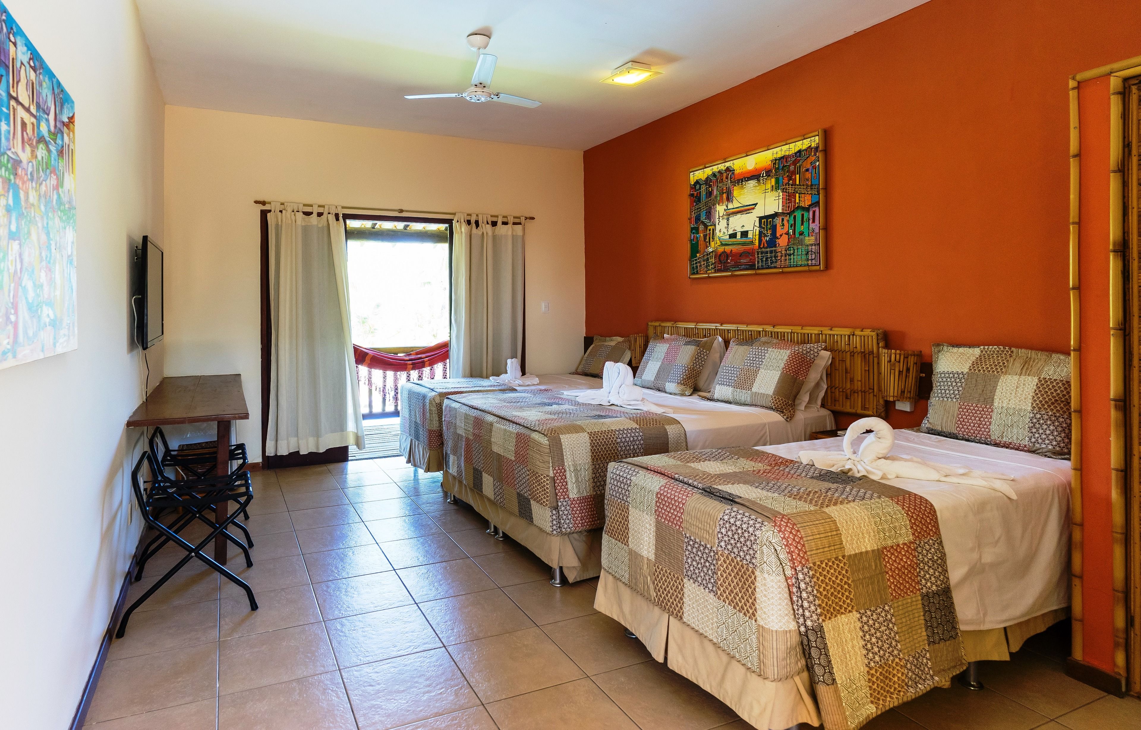 A hotel room with two beds, a dining table, and a TV.