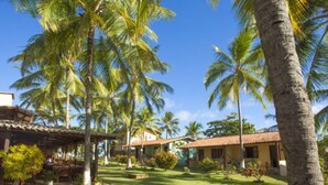 Ett tropiskt semesterparadis med palmer, en täckt uteplats och en välskött gräsmatta.