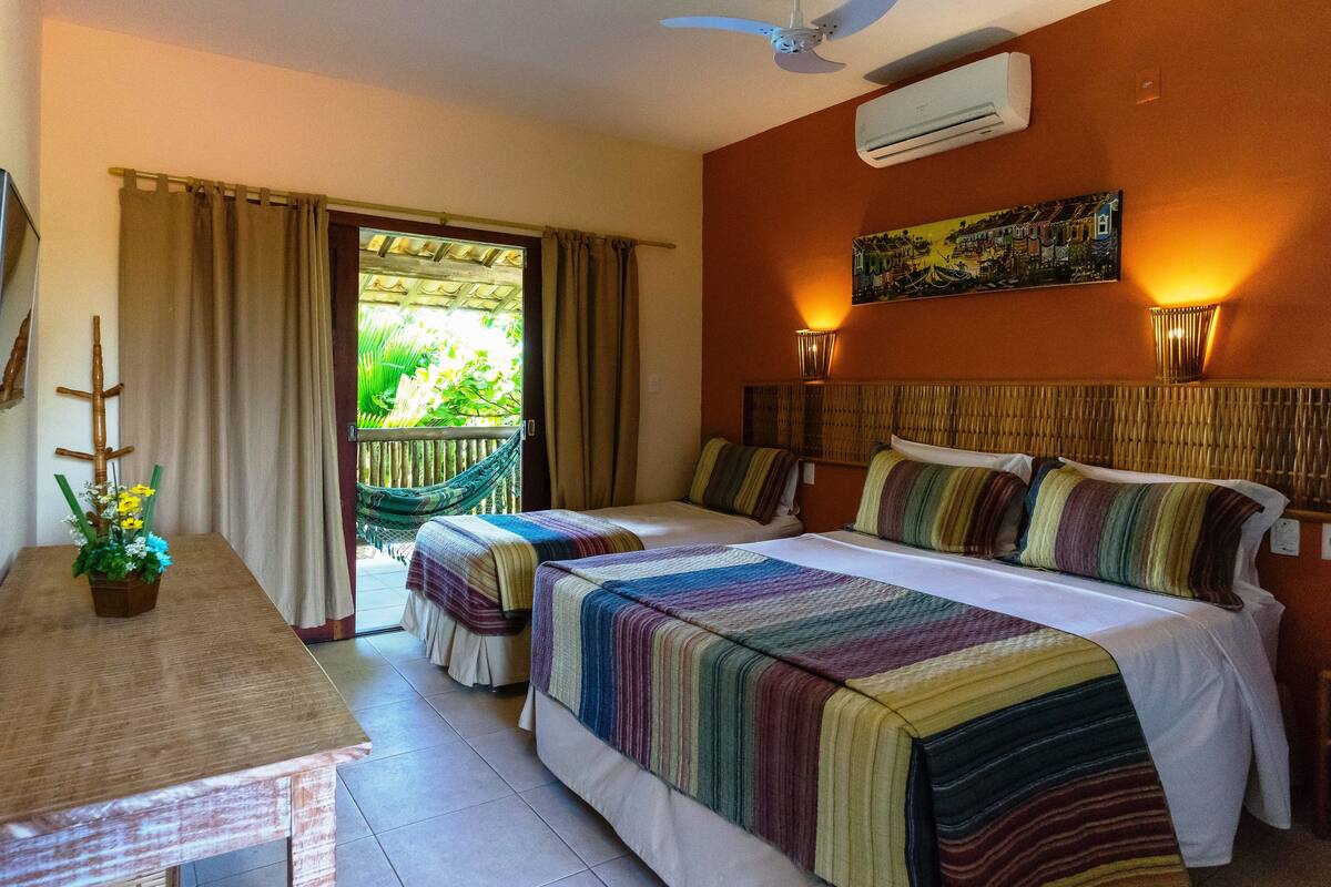 Une chambre d’hôtel avec deux lits, un bureau, une chaise, un hamac et un téléviseur.