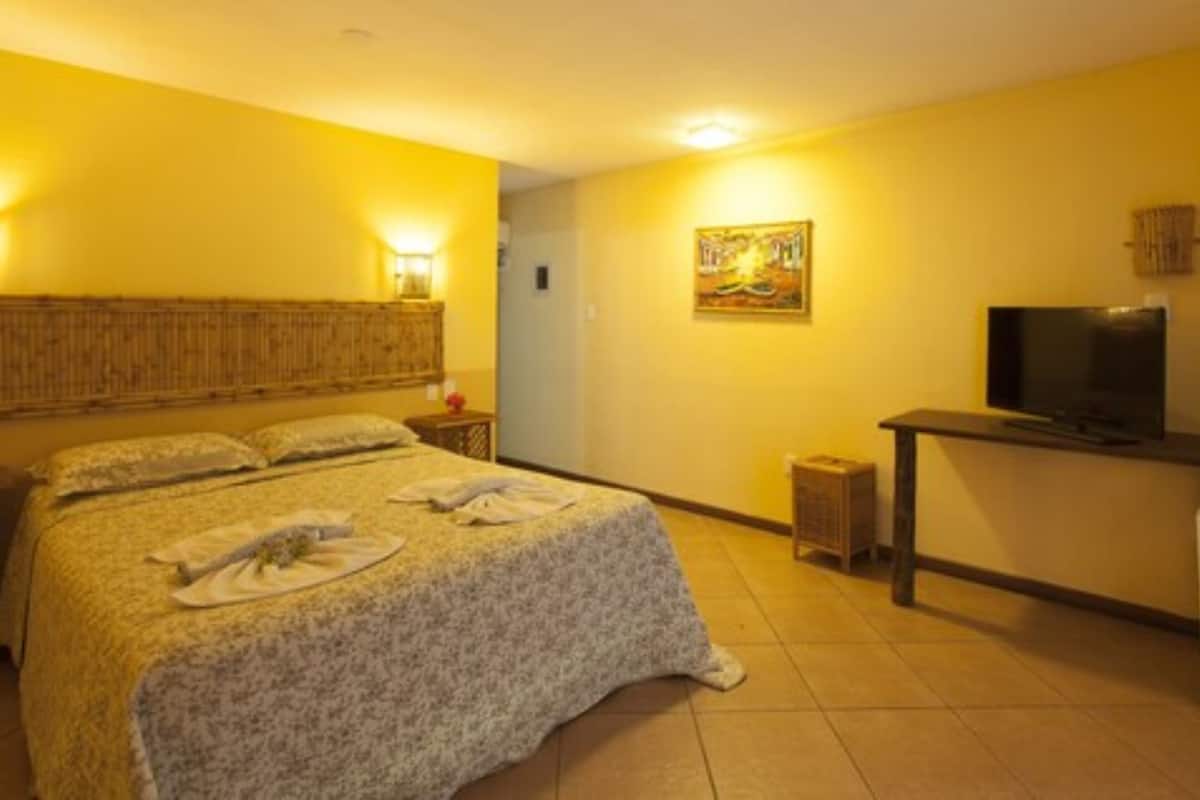 Une chambre d’hôtel avec un lit, une télévision, une petite table et un tableau accroché au mur.