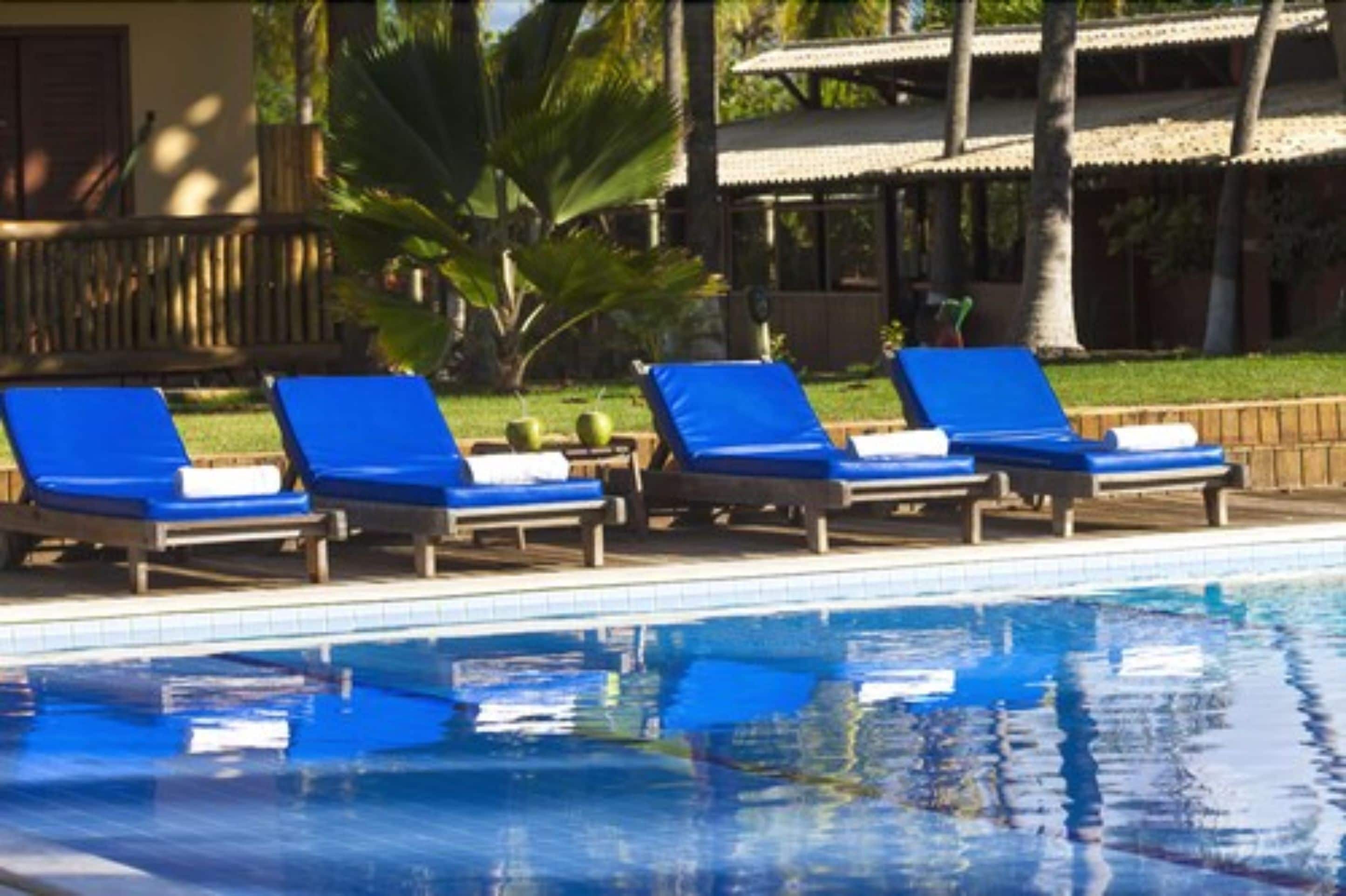 Uma área à beira da piscina com espreguiçadeiras e piscina.