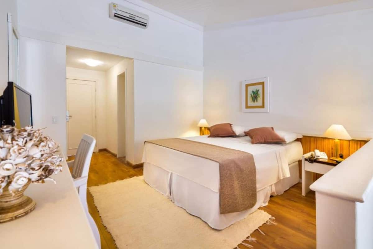 Una habitación de hotel con una cama, mesitas de noche, un escritorio y una silla.