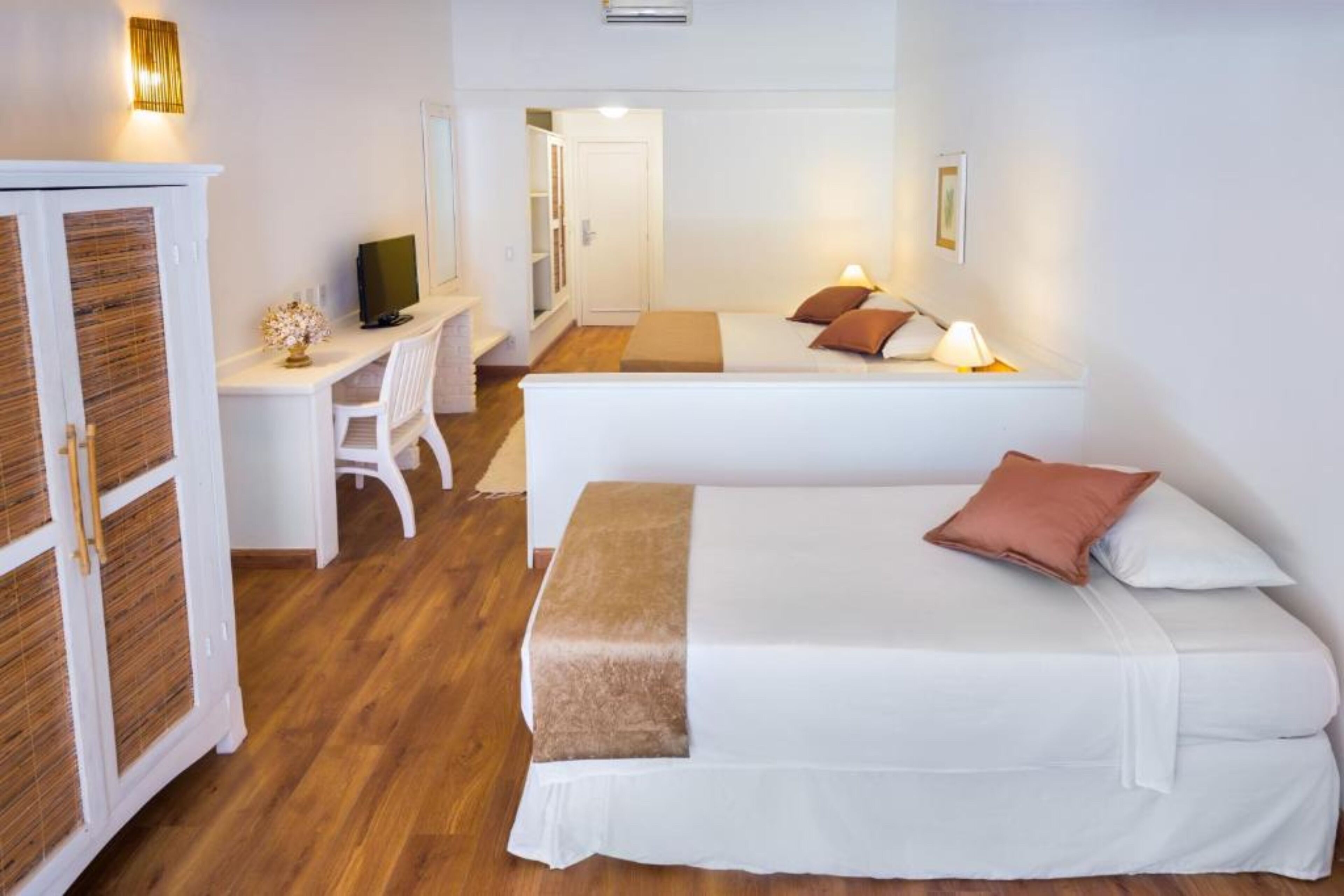 Ein Hotelzimmer mit zwei Betten, einem Schreibtisch, einem Stuhl und einem Kleiderschrank.