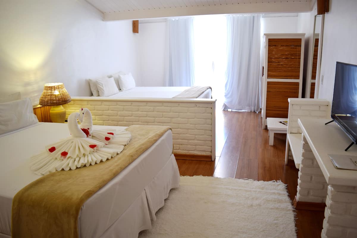 Habitación de hotel con cama, escritorio con una computadora portátil, televisión y armario de madera.