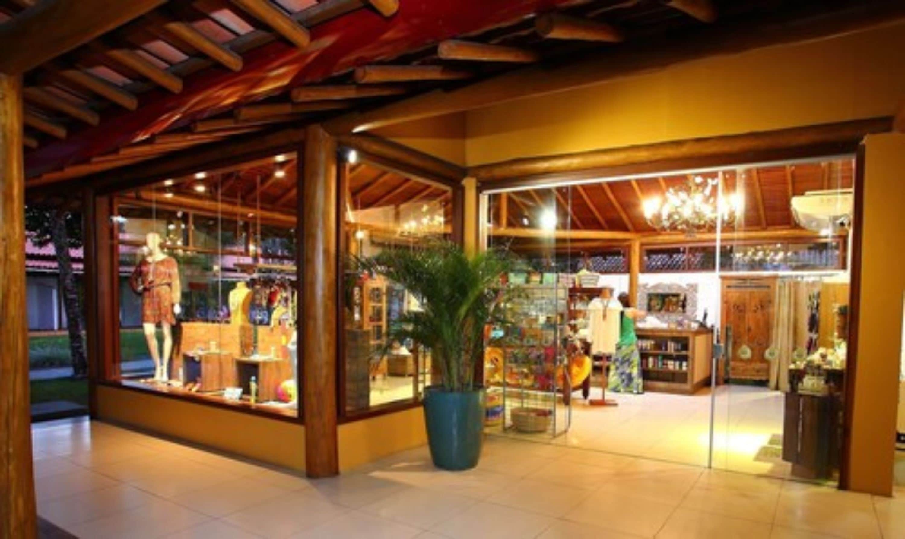 Et boutiquehotel med facade i træ, store glasruder og en stor potteplante i midten.