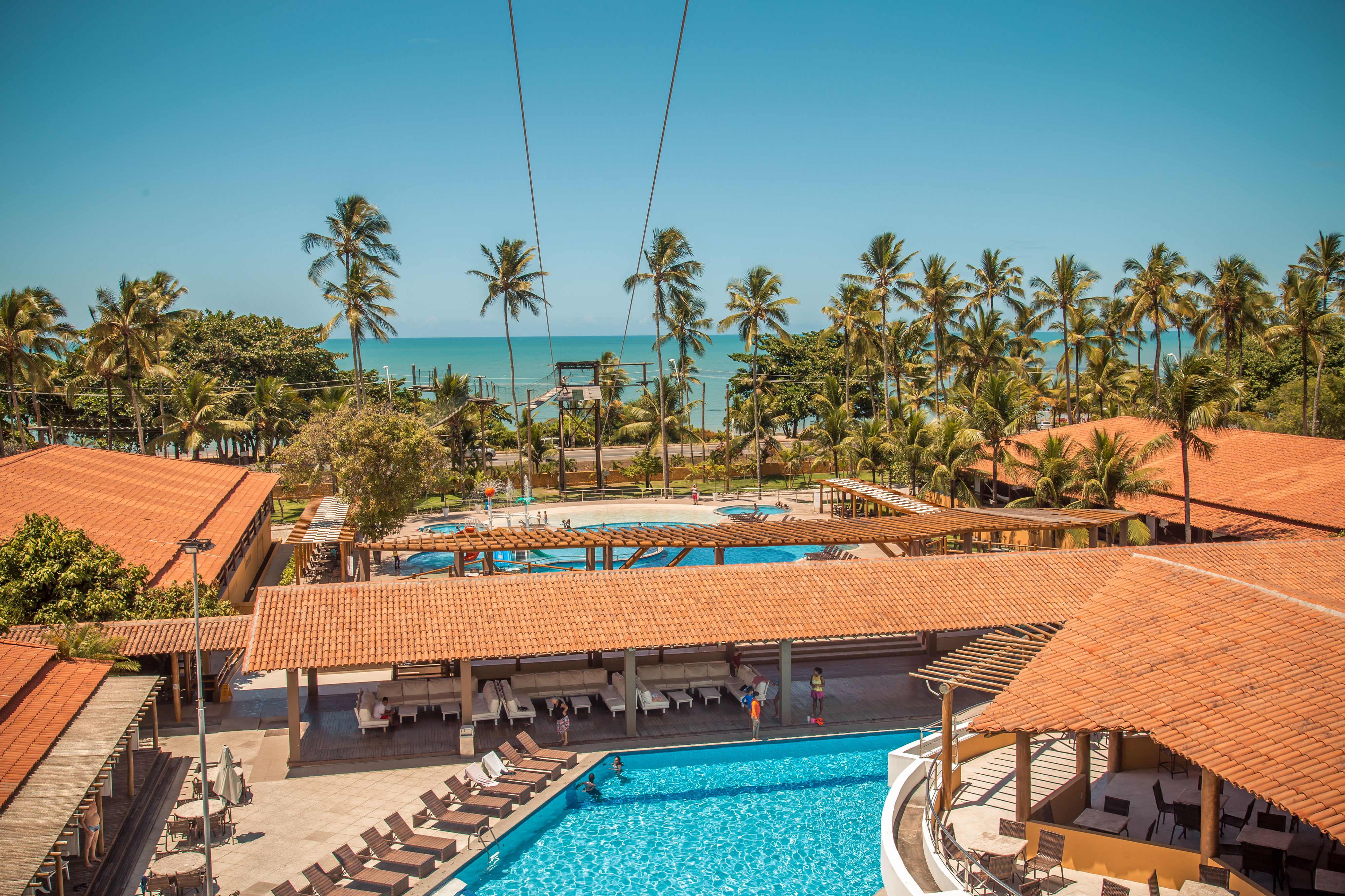 A resort with a swimming pool, lounge areas, and palm trees.