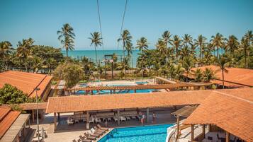 A resort with a swimming pool, lounge areas, and palm trees.