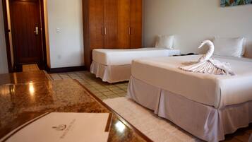 Quarto de hotel com duas camas, um guarda-roupa de madeira, bancada de mármore e toalha em formato de cisne.