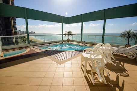 Una piscina al aire libre, sombrillas, sillones reclinables de piscina