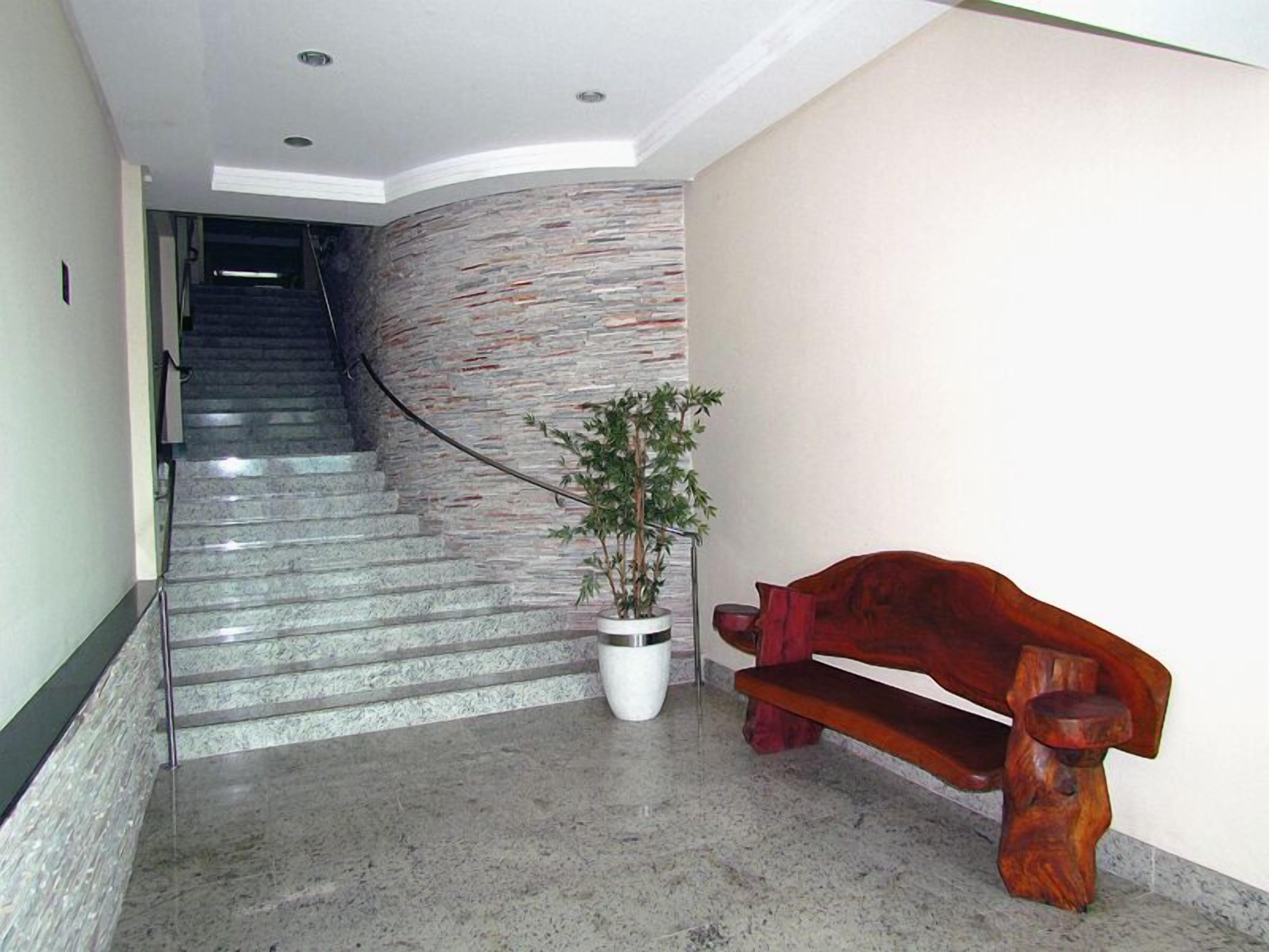Una escalera con un muro de piedra, una planta en maceta y un banco de madera.
