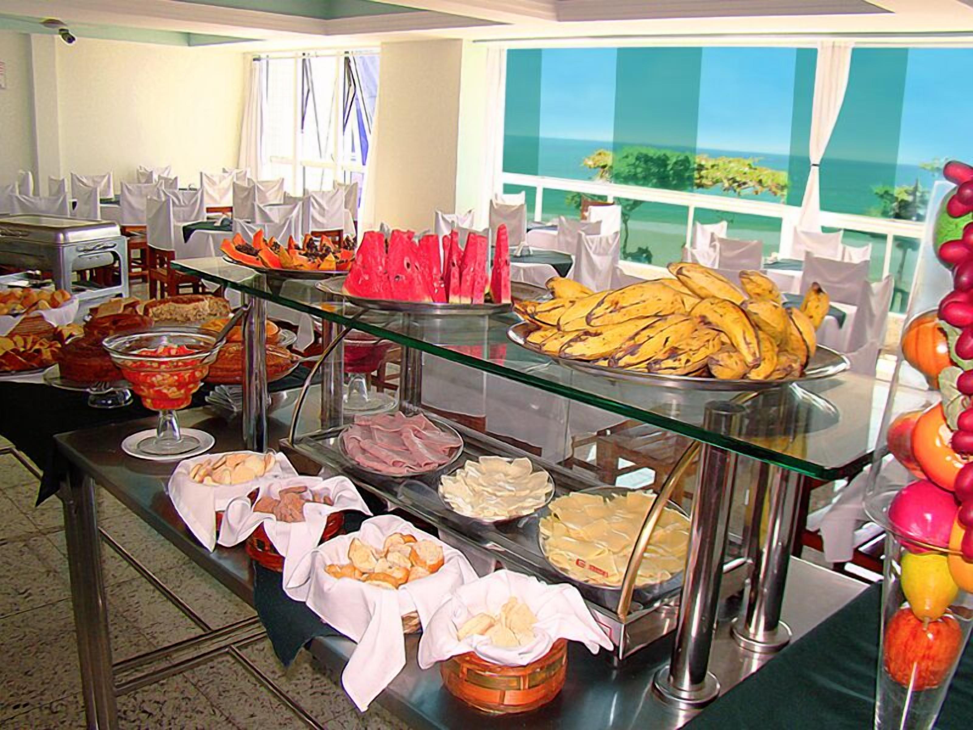 A buffet with various food items and a view of the ocean through large windows.