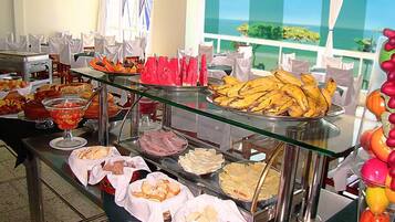 A buffet with various food items and a view of the ocean through large windows.