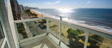 A balcony with a view of the beach and ocean.