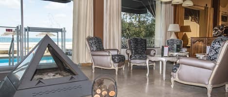 A spacious living room with a fireplace, comfortable seating, and a view of the beach.