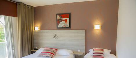 A hotel room with two beds, a wooden headboard, a painting, and a window with curtains.