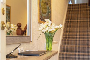 A reception desk with a vase of white flowers, a mirror, and a check-in counter.