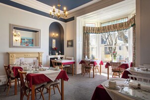 A dining area with tables set for service, a fireplace, and a view of the outside.
