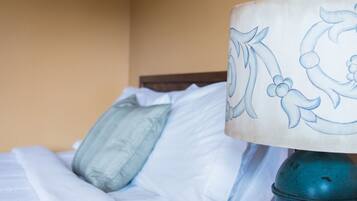 A bed with a blue pillow and a lamp with a floral design.
