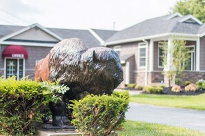 A large bear statue in front of a building with a red awning and a brick facade.