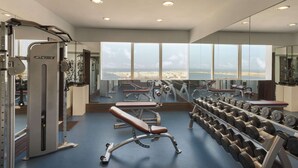Une salle de sport équipée de matériel de musculation, de bancs et d’haltères.