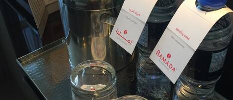 A tray with water bottles labeled 'RAMADA' and a menu board in the background.