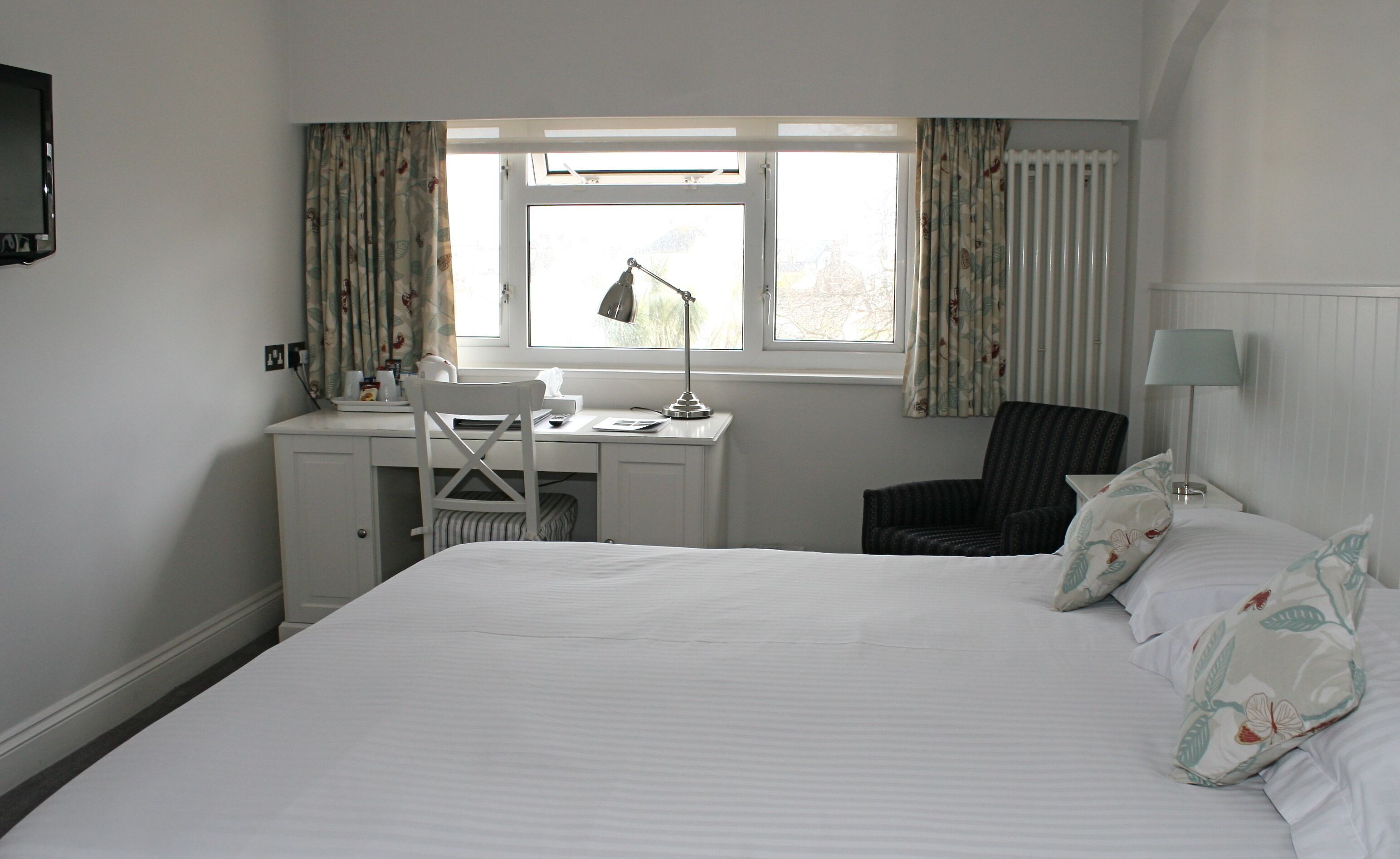Una habitación de hotel con cama, escritorio y silla.