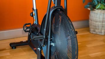 Una bicicleta estática en una habitación con suelo de madera y pared naranja.