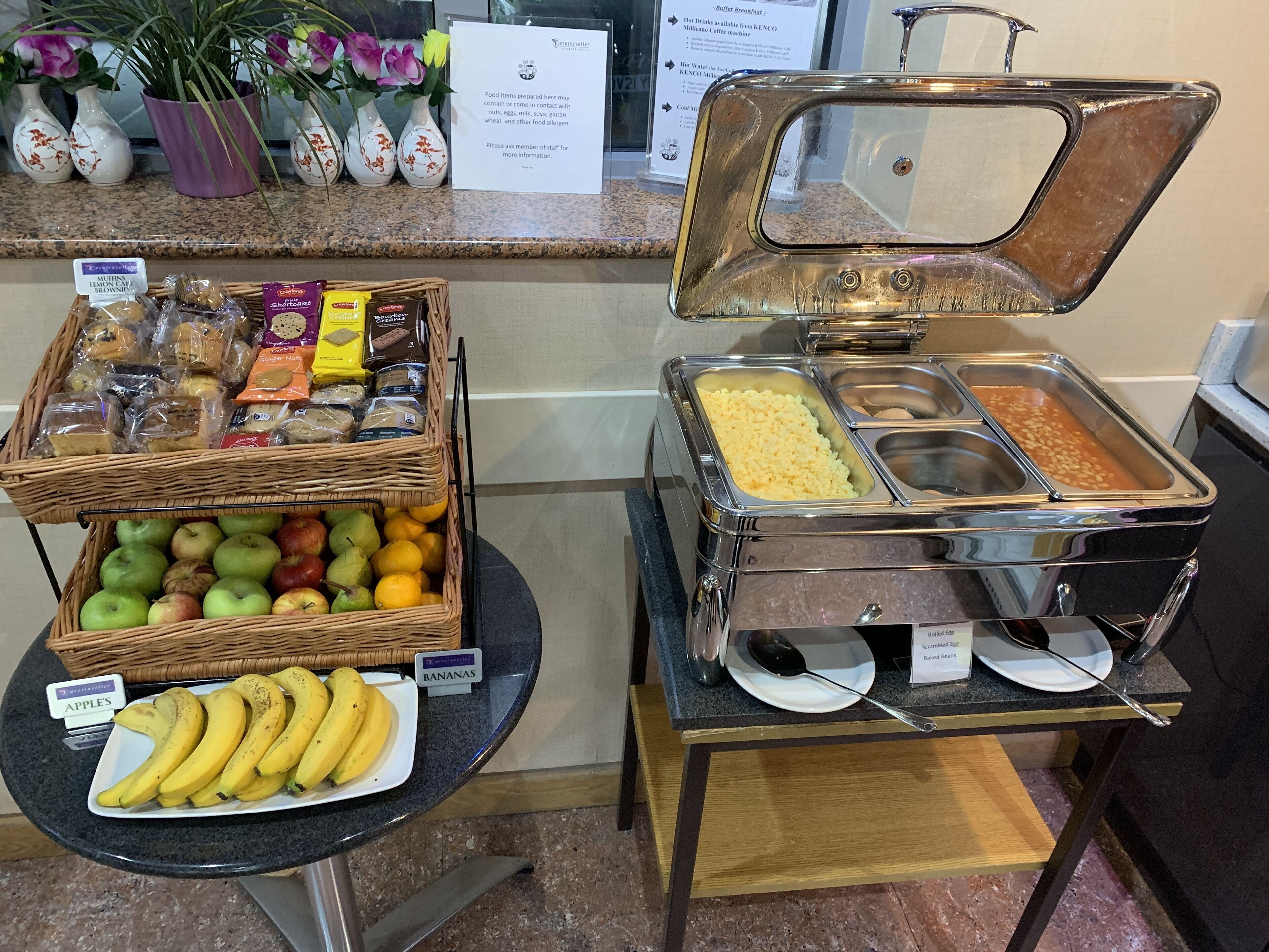 A buffet setup with various food items including fruits, baked goods, and a hot beverage station.