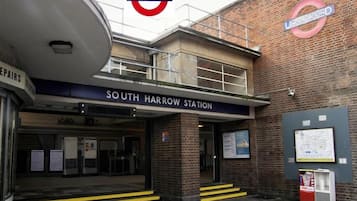 Entrada de la estación South Harrow, con fachada de ladrillo, un cartel y un panel informativo con mapa.