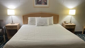 A neatly made bed with white bedding, two bedside tables with lamps, and a framed picture on the wall.