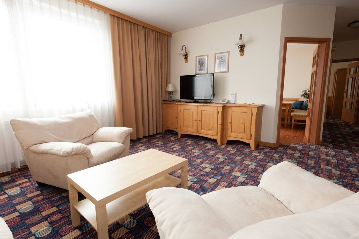Una habitación de hotel con sofá, una mesita, televisor y armario.
