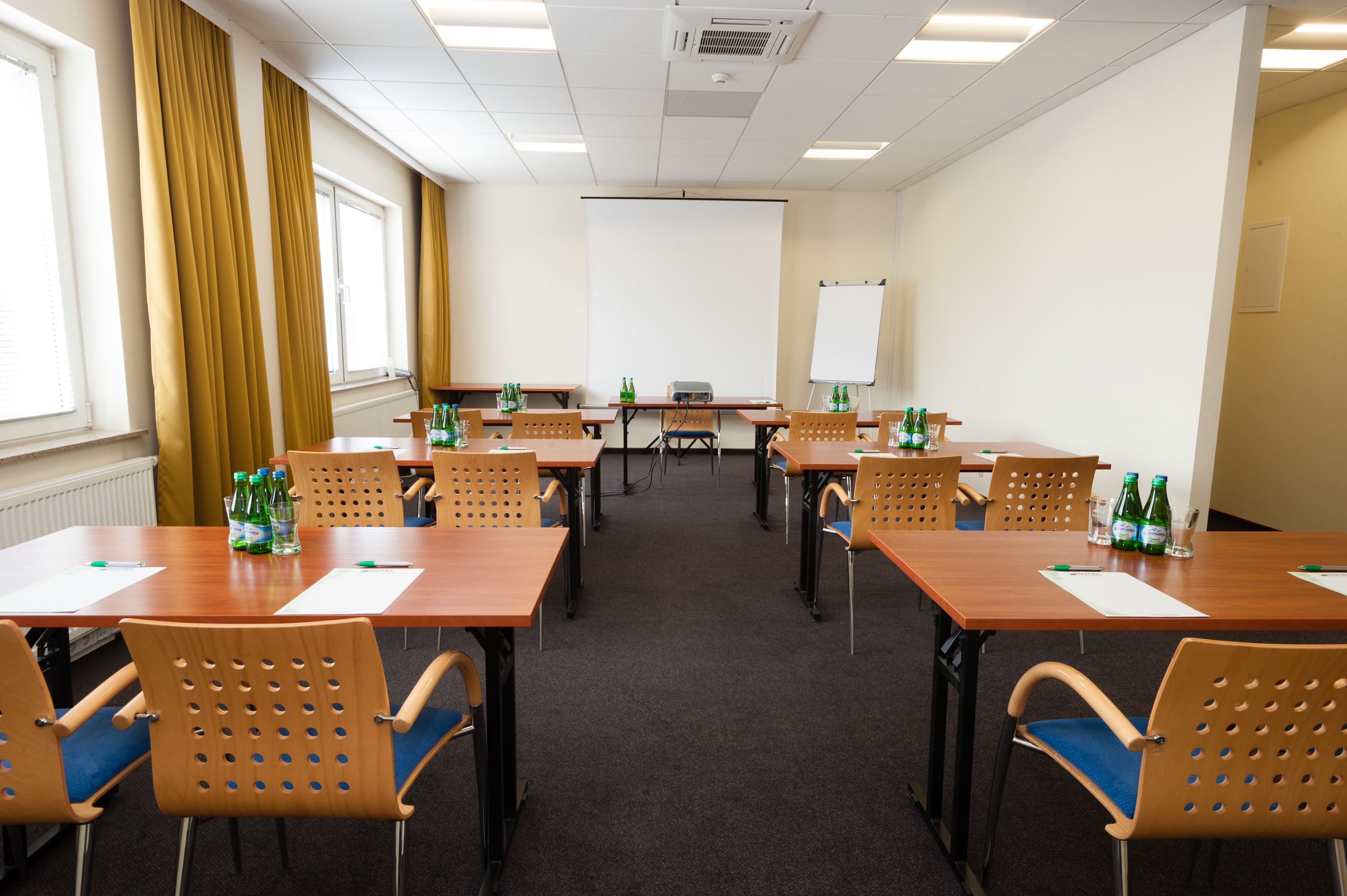 A conference room with tables, chairs, and a projector screen.