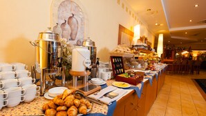 A breakfast buffet with coffee machines, croissants, and various breakfast items. - Hotel Partner (Warsaw)