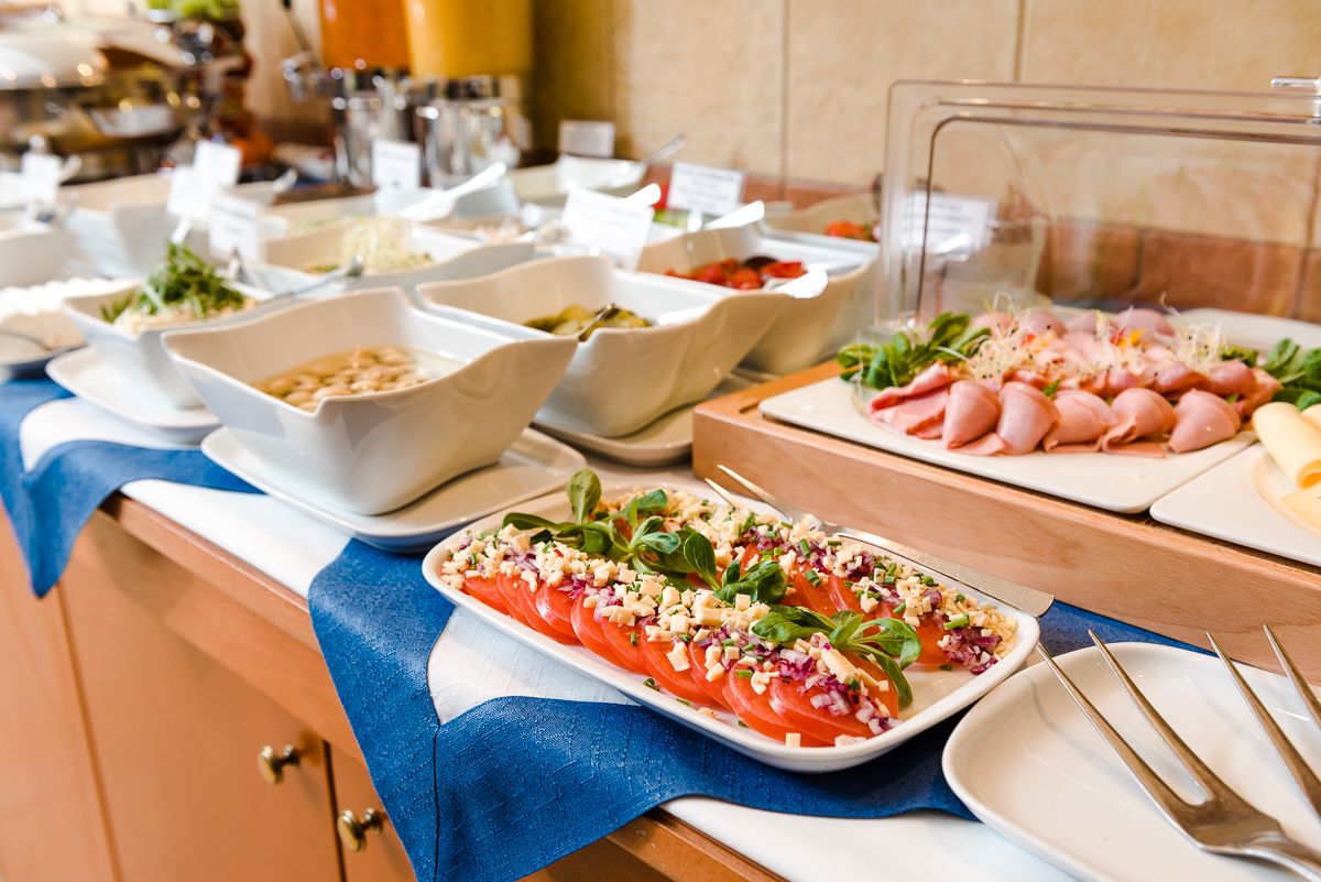 A buffet with various dishes including a salmon salad, a meat platter, and several side dishes.