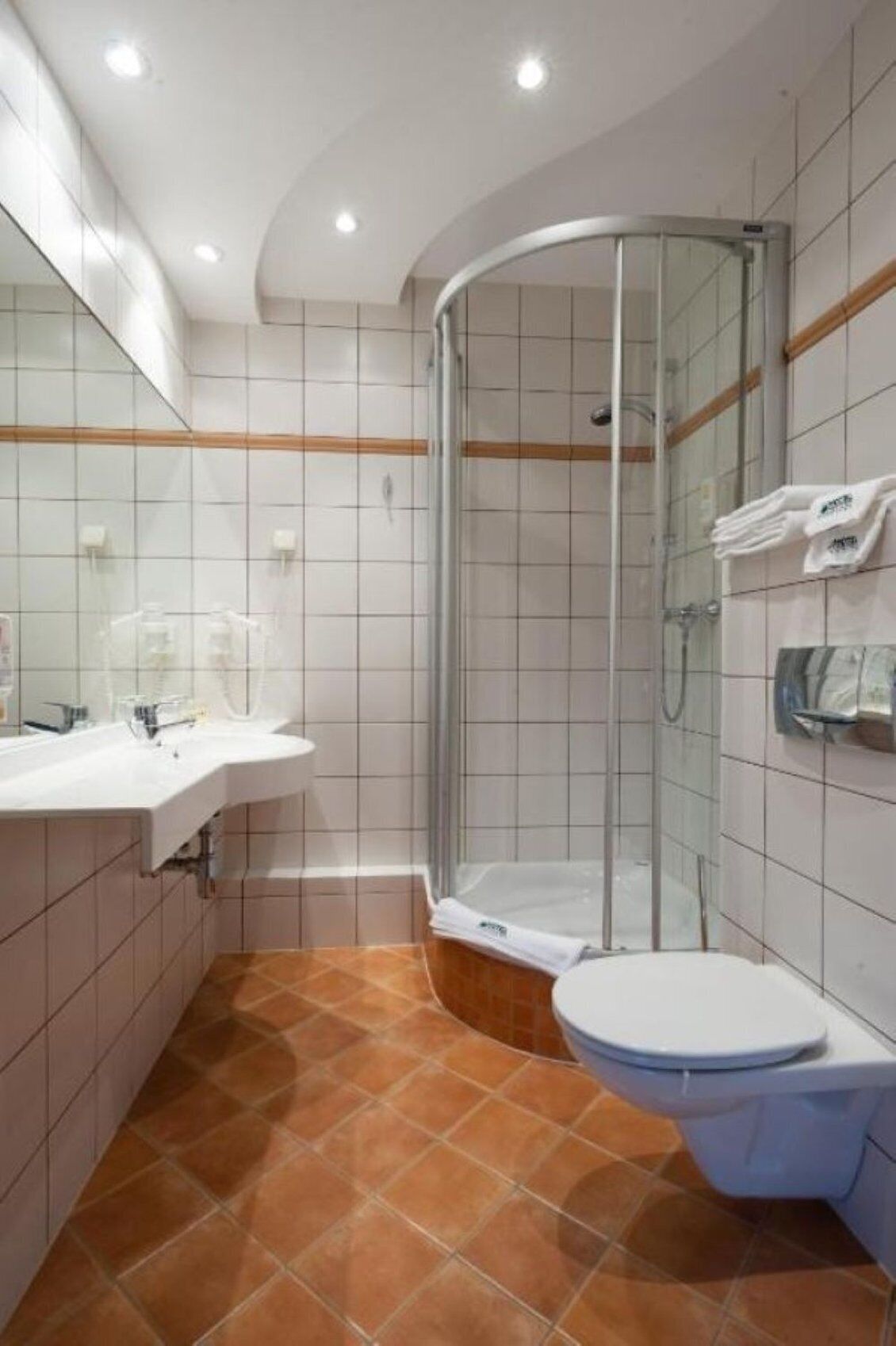 Un baño con cabina de ducha de vidrio, lavamanos blanco y un inodoro.