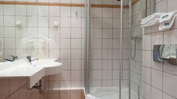 Un baño con cabina de ducha de vidrio, lavamanos blanco y un inodoro.