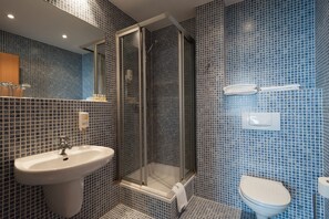 A bathroom with a sink, toilet, and glass-enclosed shower.