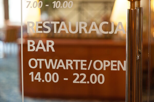A restaurant sign with operating hours. - Hotel Partner (Warsaw)