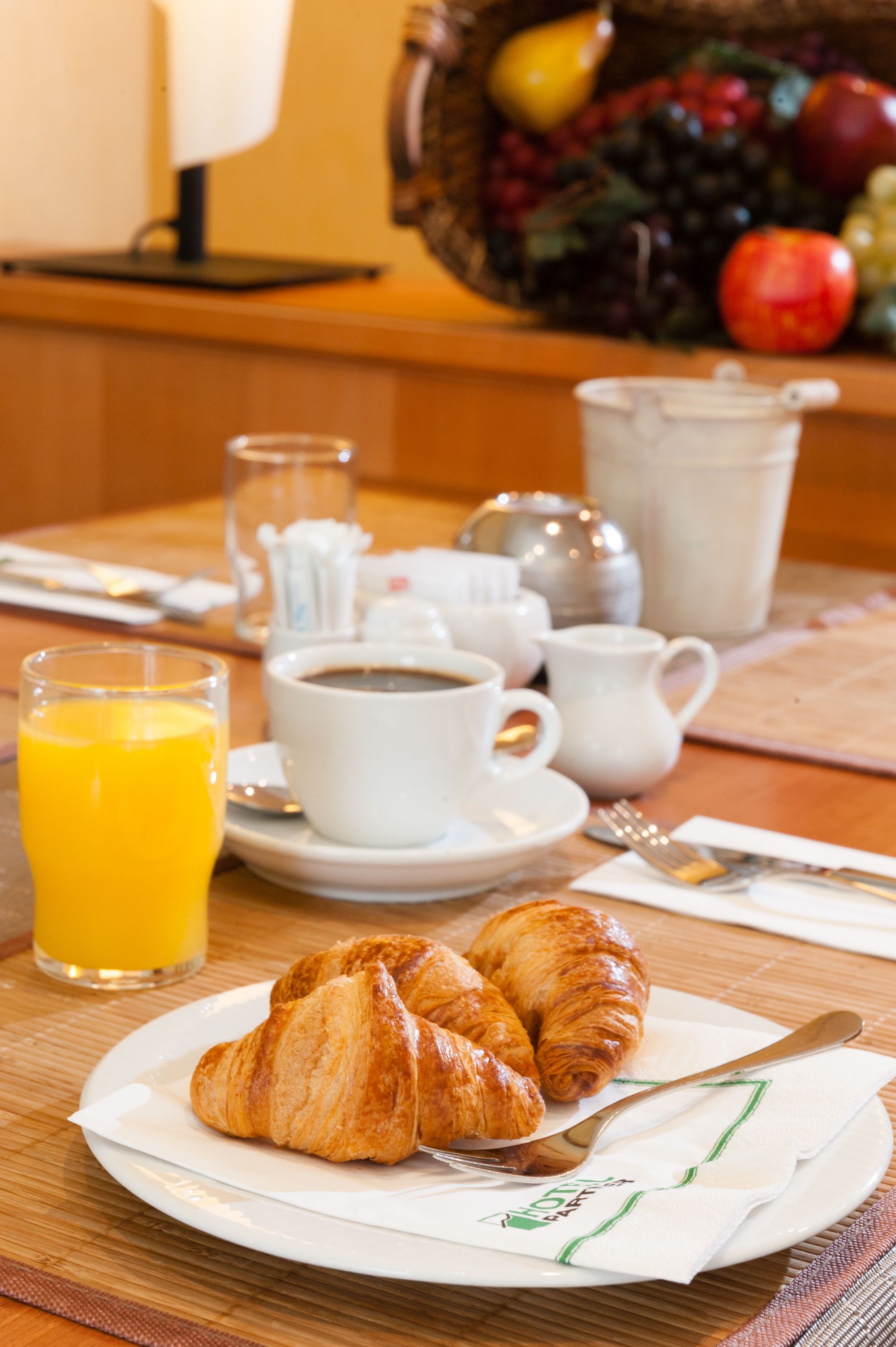 Una mesa de desayuno con cruasanes, café y jugo.