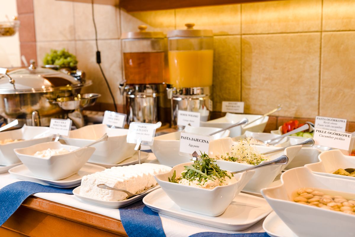 A buffet with labeled dishes including pasta, eggs, and pickles.