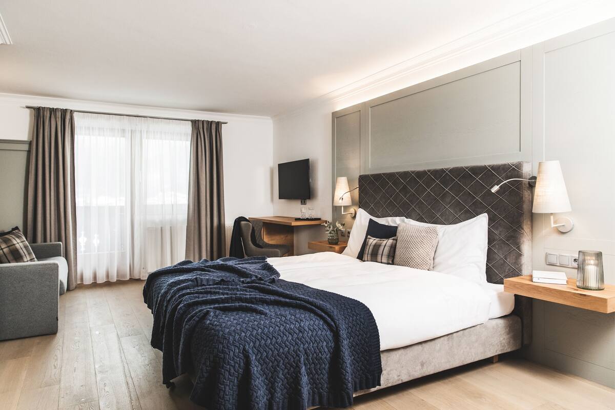 Een hotelkamer met een groot bed, een bureau, een stoel, een televisie en een lamp.