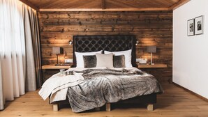 Een slaapkamer met een houten plafond, een bed met een donkere hoofdbord, twee nachtlampjes en een nachtkastje met een lamp.