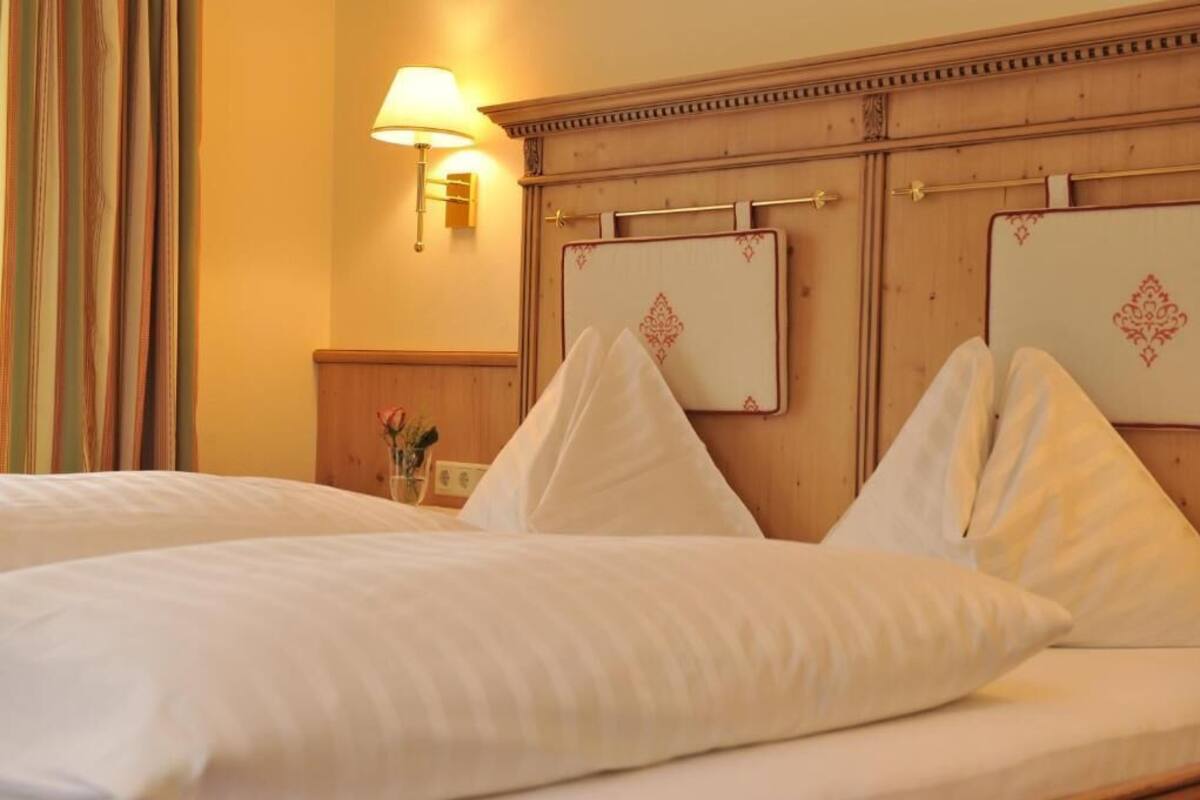 Een hotelkamer met een bed, nachtkastje, lamp en een spiegel aan de muur.