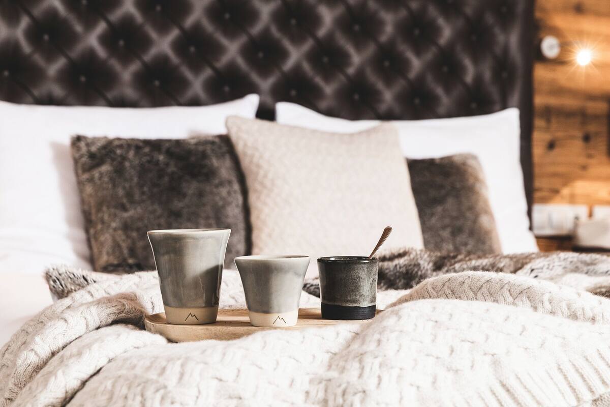 Een bed met kussens en een nachtkastje met drie bekers en een lepel.
