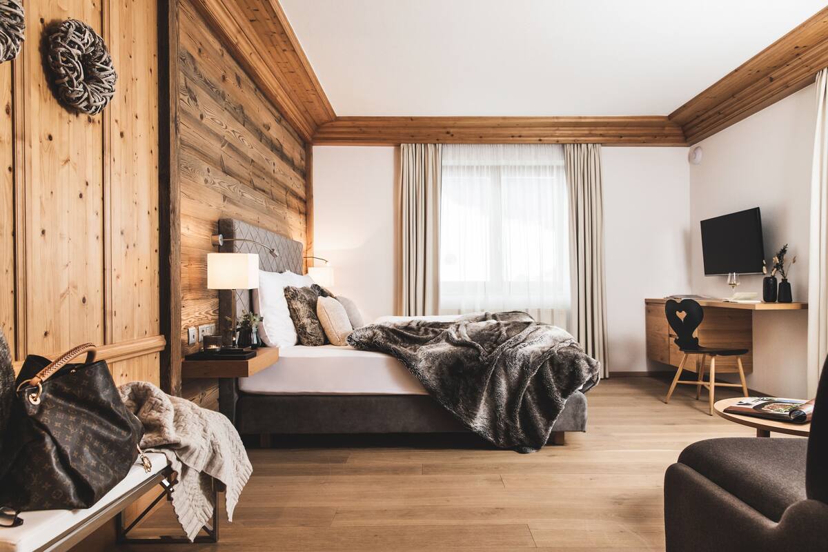 Een slaapkamer met een bed, nachtkastje, lamp en een televisie op een bureau.